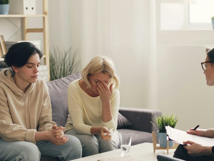 A counselor takes notes during a calm, supportive conversation with two women